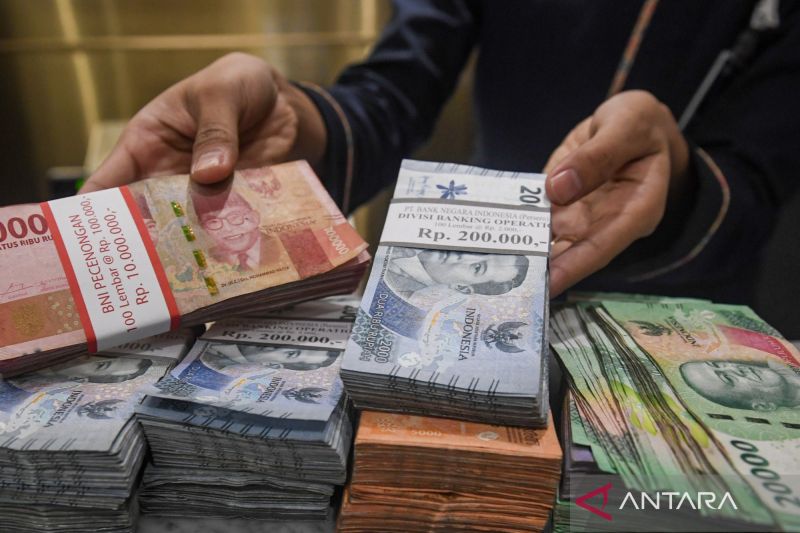 Petugas menunjukkan lembaran uang rupiah